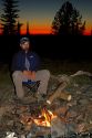 Man sitting by a camp fire at the summit of Green Mountain along the historic Magruder Corridor road that devides the Frannk Church-River of No Return Wilderness Area and the Selway-Bitterwoot Wilderness in Idaho, USA. MR