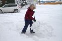 Woman shoveling winter snow off of a sidewalk in Boise, Idaho, USA.