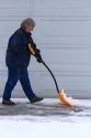Woman shoveling winter snow of off a driveway in Boise, Idaho, USA.