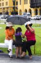 Women shading themselves from the hot sun with an umbrella at the Plaza Mayor or Plaza de Armas of Lima, Peru.