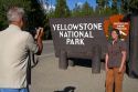 Tourists take a photo in front of the Yellowstone National Park entrance sign, West Yellowstone, Montana, USA.