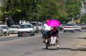Woman shading herself with an umbrella while riding in a trishaw in (Rangoon) Yangon, (Burma) Myanmar.