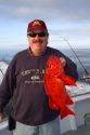 Fisherman holding his catch of a Vermillion Rockfish in the Pacific Ocean off the coast of Newport, Oregon, USA.