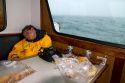 Teenage boy taking a nap on a chartered fishing boat in the pacific ocean near Newport, Oregon, USA.