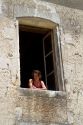 Young woman looks out the window of a french farm house near Angouleme in southwestern France.