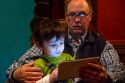 Man reading from an iPad tablet to a young boy in Boise, Idaho, USA.