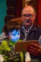 Man reading from an iPad tablet to a young boy in Boise, Idaho, USA.