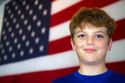 Ten year old american boy standing in front of an american flag in Charleston, South Carolina, USA. MR
